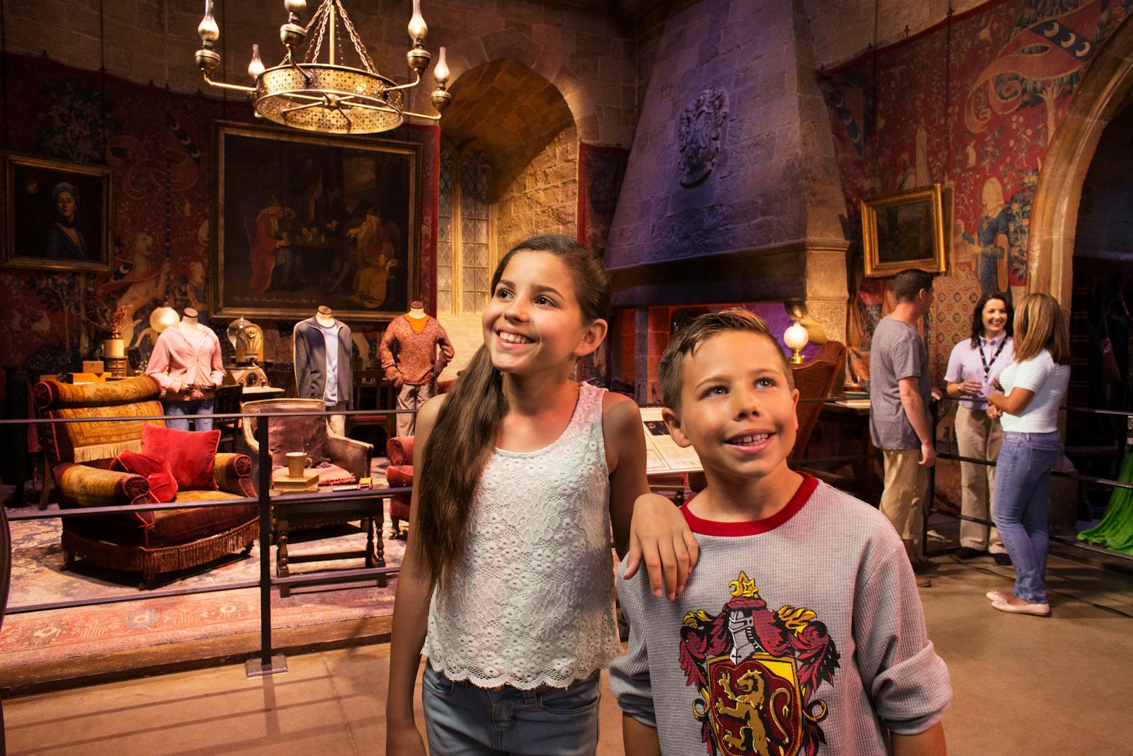 两名微笑的儿童在 The Making of Harry Potter (Warner Bros. Studio Tour) 的格兰芬多公共休息室前